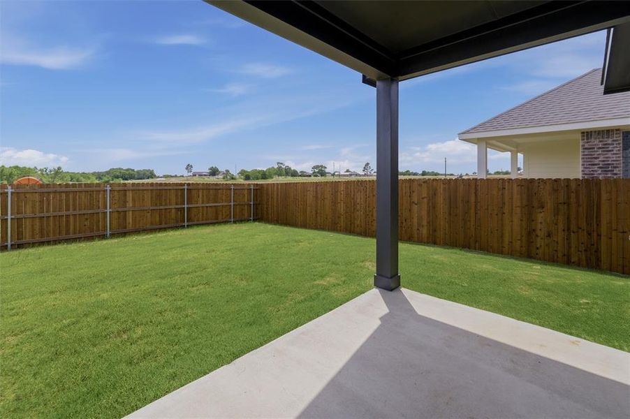 Expansive backyard featuring a covered patio, manicured lawn, and privacy fencing