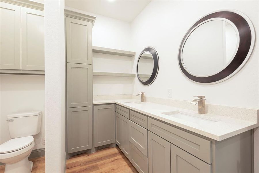 Full bath with double vanity and light wood-type flooring