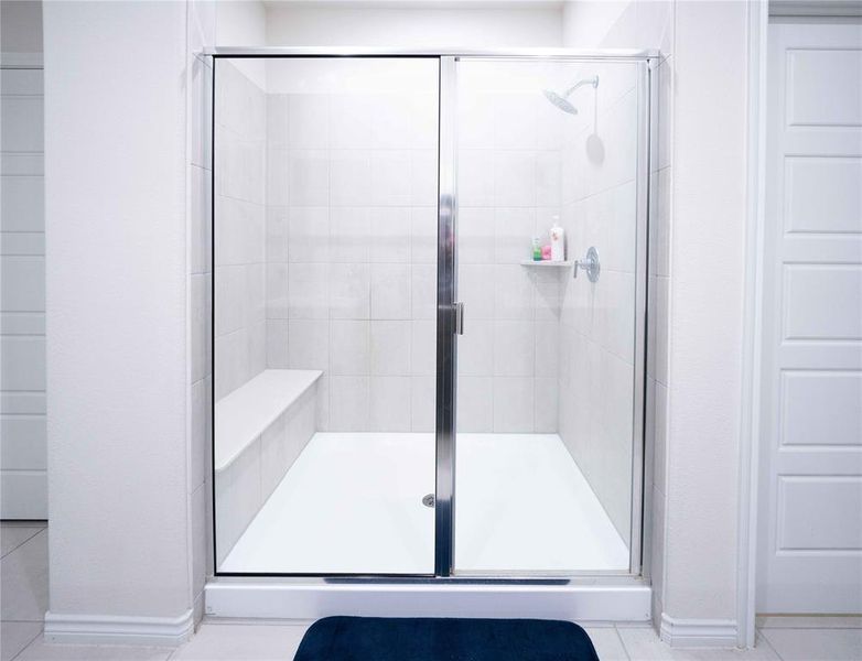 Glass-enclosed shower featuring white subway tile, a built-in shower bench, and a mounted shower head Glass-enclosed shower featuring white subway tile, a built-in shower bench, and a mounted shower head