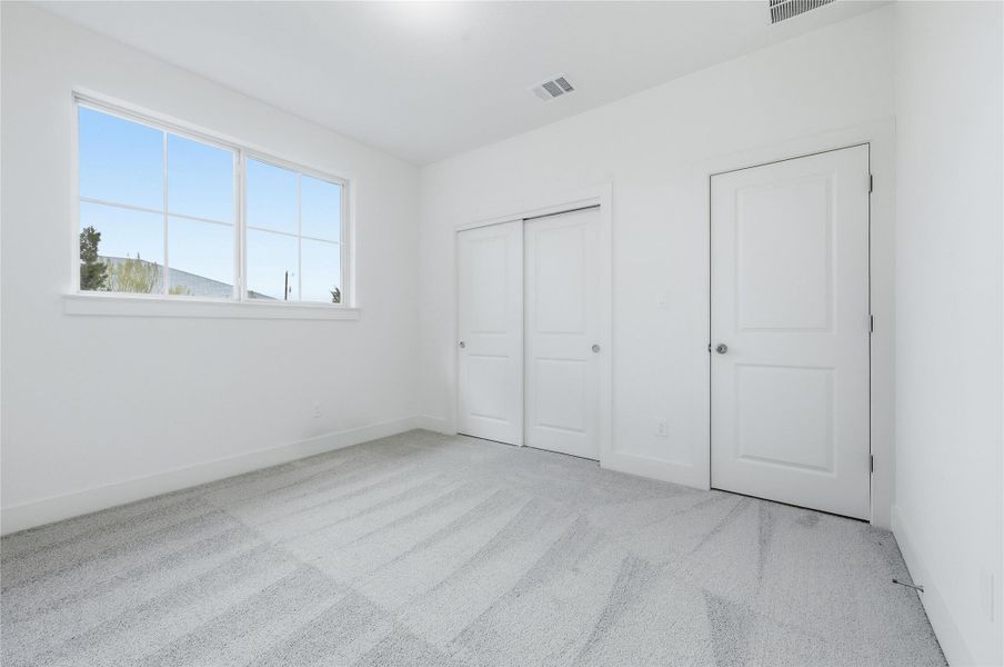 Unfurnished bedroom with light colored carpet and a closet
