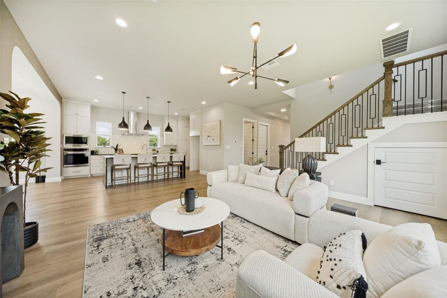 An open-concept living space integrates a modern kitchen, dining island, and a sleek living room with a striking staircase. An open-concept living space integrates a modern kitchen, dining island, and a sleek living room with a striking staircase.