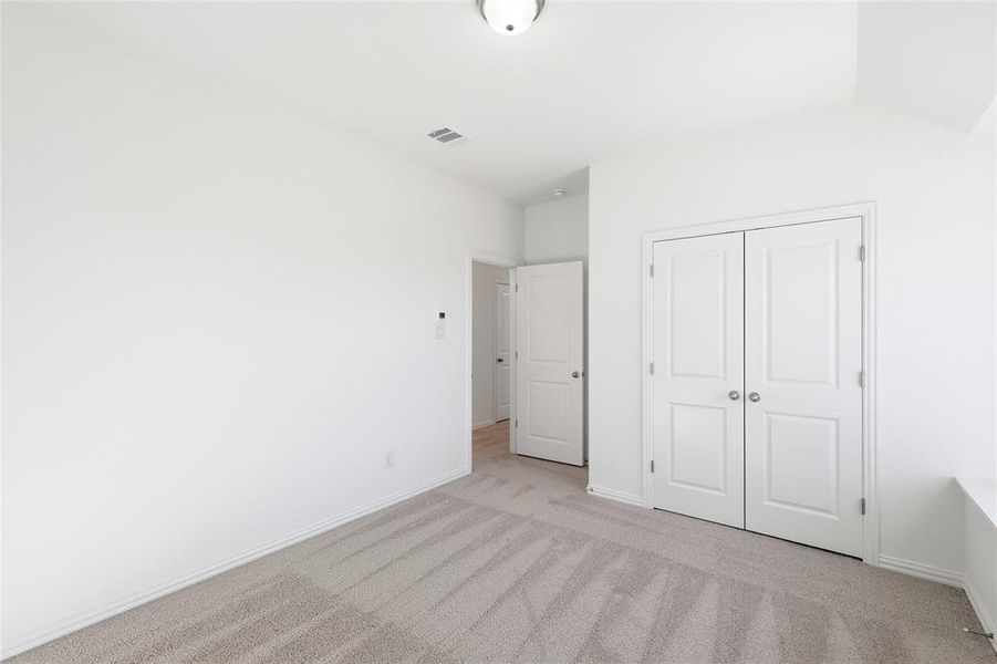 Neutral-toned carpeted interior space featuring white walls and trim