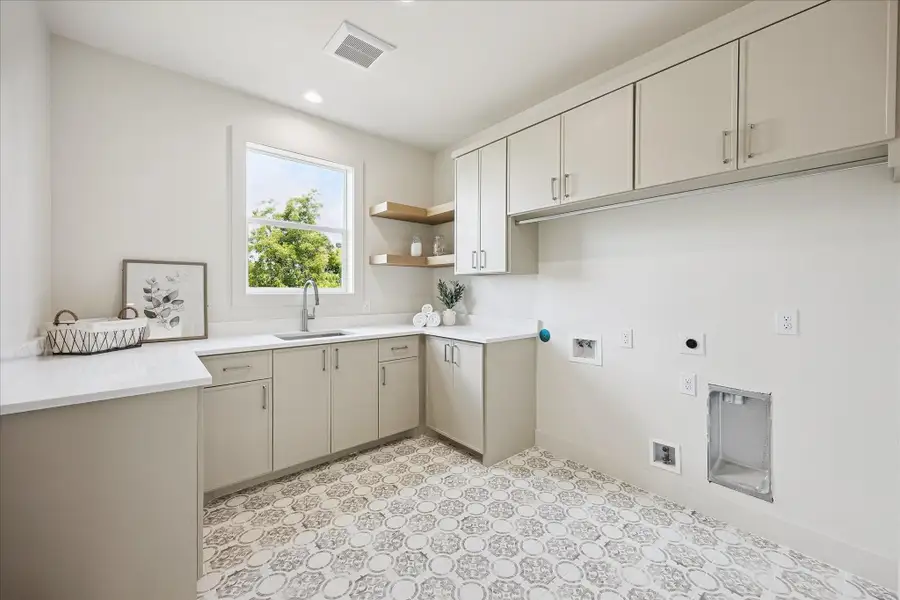 Laundry feels a little less like a chore in this spacious upstairs utility room, complete with a deep sink, custom cabinetry with ample storage and designer flooring, all conveniently located near the bedrooms.