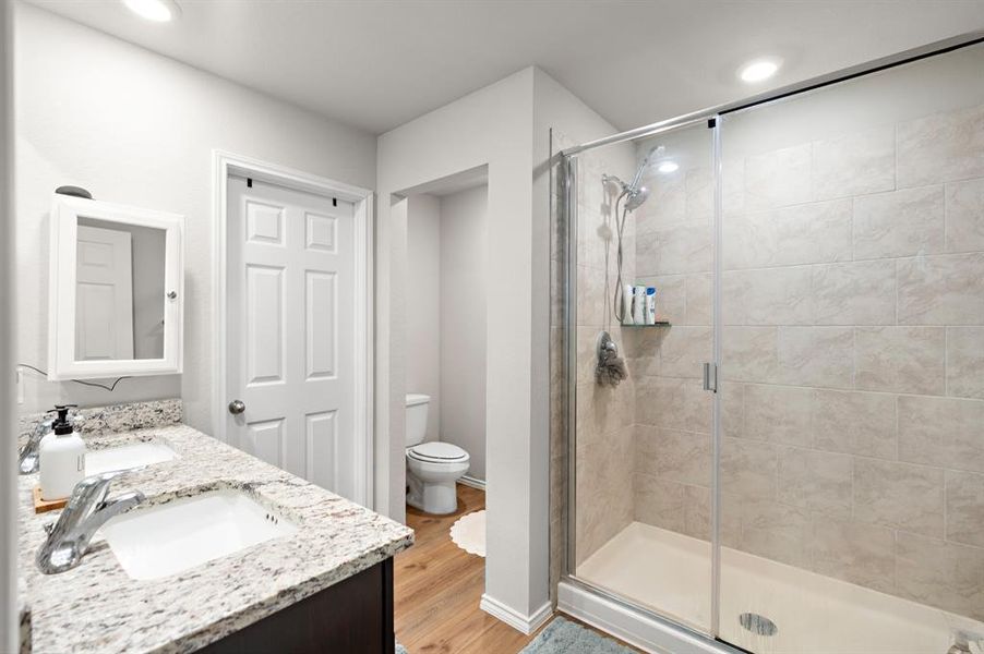 Bathroom featuring double vanity, a stall shower, light wood finished floors, and recessed lighting Bathroom featuring double vanity, a stall shower, light wood finished floors, and recessed lighting