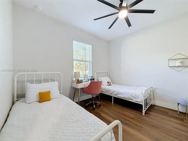 Neutral wall paint, wood-finish flooring, single-hung window, and a multi-blade ceiling fan with integrated lighting