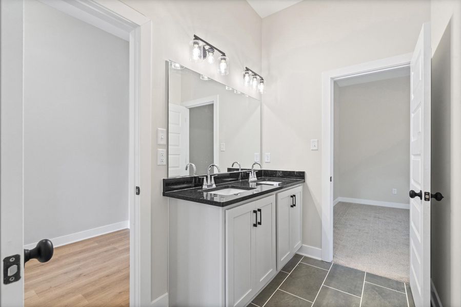 Double vanity featuring a dark countertop, undermount sinks, and brushed nickel faucets Double vanity featuring a dark countertop, undermount sinks, and brushed nickel faucets