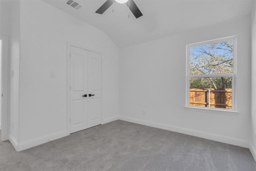Third bedroom featuring high ceiling, light carpet, a closet, and ceiling fan