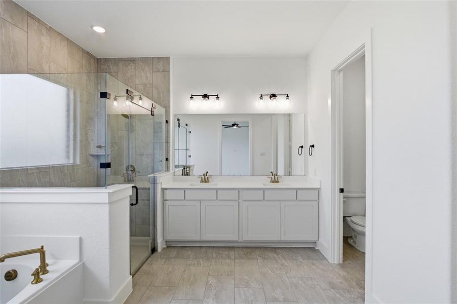 Full bathroom featuring double vanity, a shower stall, a garden tub, and recessed lighting