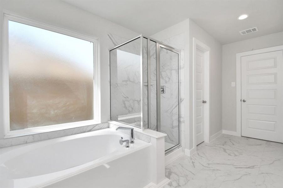 The primary en-suite has a soaking tub to give you that spa experience. The large privacy window allow lots of nature light in the space. Sample photo of completed home with similar floor plan. As-built interior colors and selections may vary.