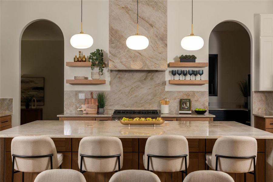 Bar area with backsplash, arched walkways, light stone counters, open shelves, and dual tone cabinetry