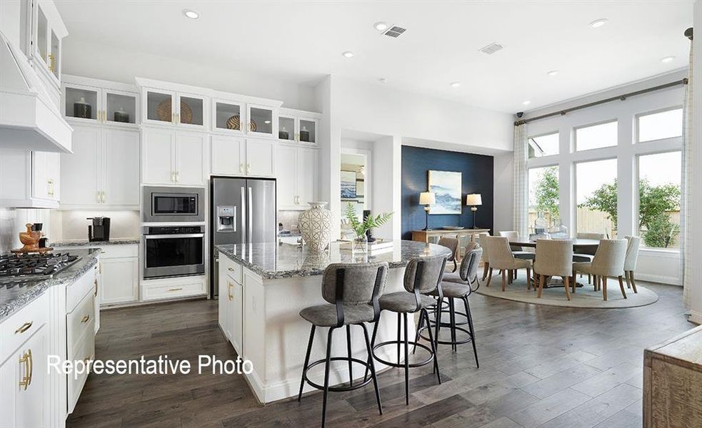 Contemporary kitchen featuring white cabinetry, integrated stainless steel appliances, a center island with bar seating, and wood-finish flooring
