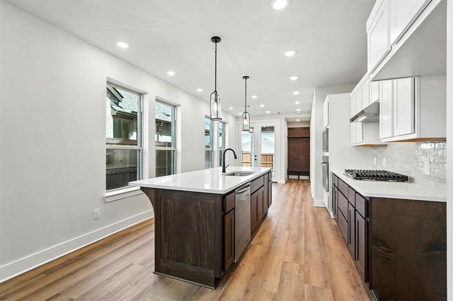 Kitchen featuring hanging light fixtures, light wood finished floors, white cabinetry, recessed lighting, and an island with sink Kitchen featuring hanging light fixtures, light wood finished floors, white cabinetry, recessed lighting, and an island with sink