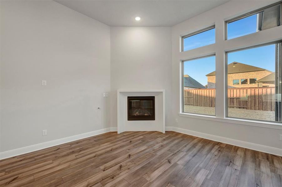 Unfurnished living room featuring wood finished floors, a glass covered fireplace, and recessed lighting