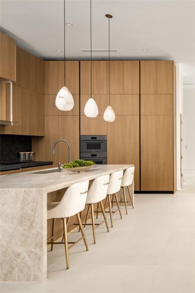 Beautifully designed kitchen featuring a waterfall island, sleek custom cabinetry, and warm, modern finishes throughout.