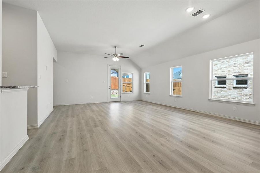 Unfurnished living room with ceiling fan, vaulted ceiling, and light wood-style floors Unfurnished living room with ceiling fan, vaulted ceiling, and light wood-style floors