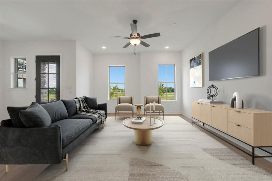 Spacious living area featuring light wood-finish flooring, recessed lighting, and a ceiling fan Spacious living area featuring light wood-finish flooring, recessed lighting, and a ceiling fan