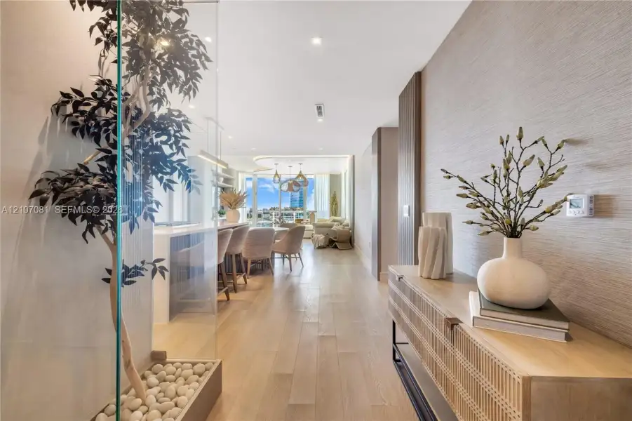 Interior featuring wood-finish flooring, textured wall coverings, recessed ceiling lighting, and a glass-enclosed decorative planter bed with stone accents Interior featuring wood-finish flooring, textured wall coverings, recessed ceiling lighting, and a glass-enclosed decorative planter bed with stone accents