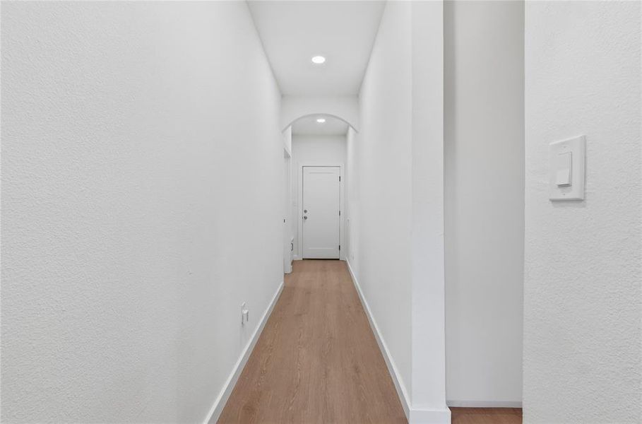 Hallway featuring light wood-finish flooring, recessed lighting, and a white interior door