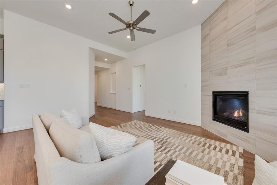 Living room with a tiled fireplace, ceiling fan, and hardwood / wood-style floors