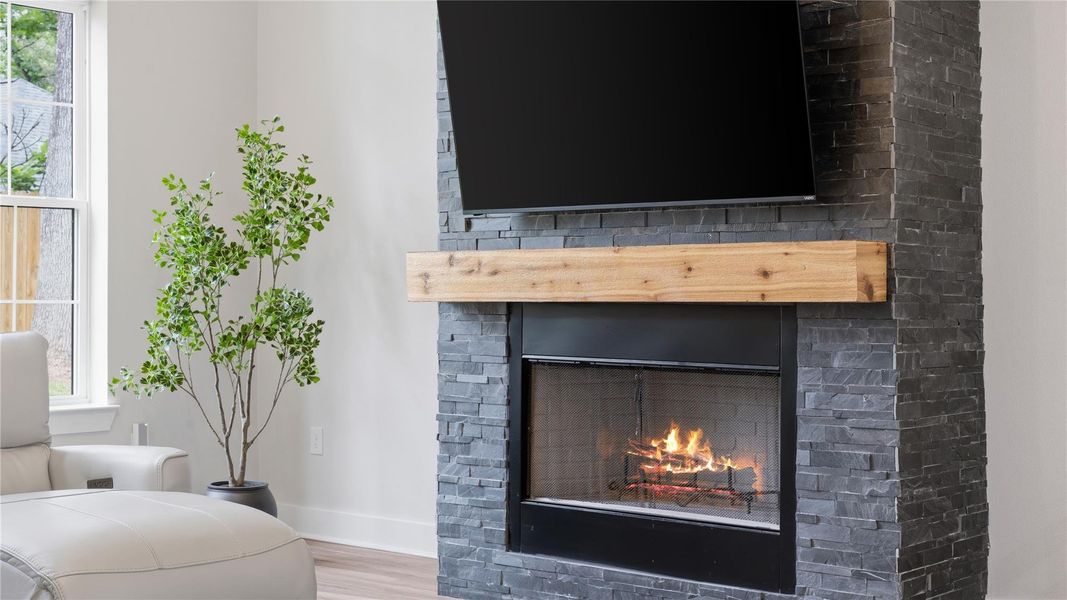 This living room has faulted ceilings, bright lighting and floor to ceiling fireplace.