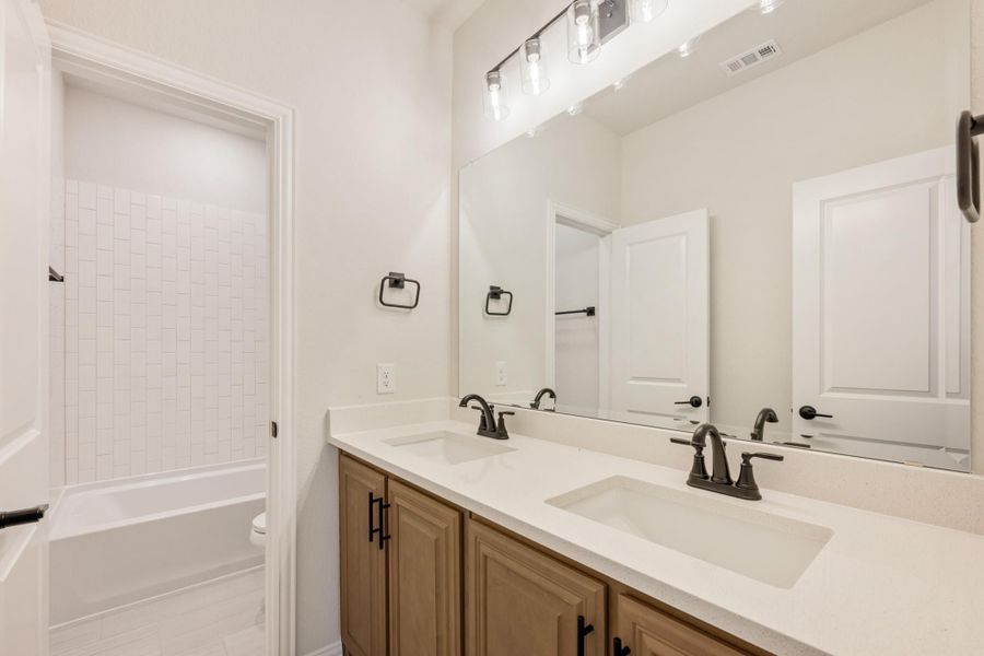 Bathroom with double sink vanity, large mirror, and tiled shower-tub combo with white walls Bathroom with double sink vanity, large mirror, and tiled shower-tub combo with white walls
