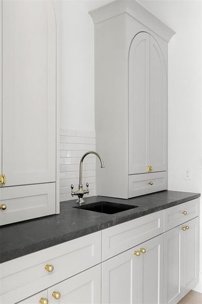 Kitchen with backsplash, sink, and white cabinets