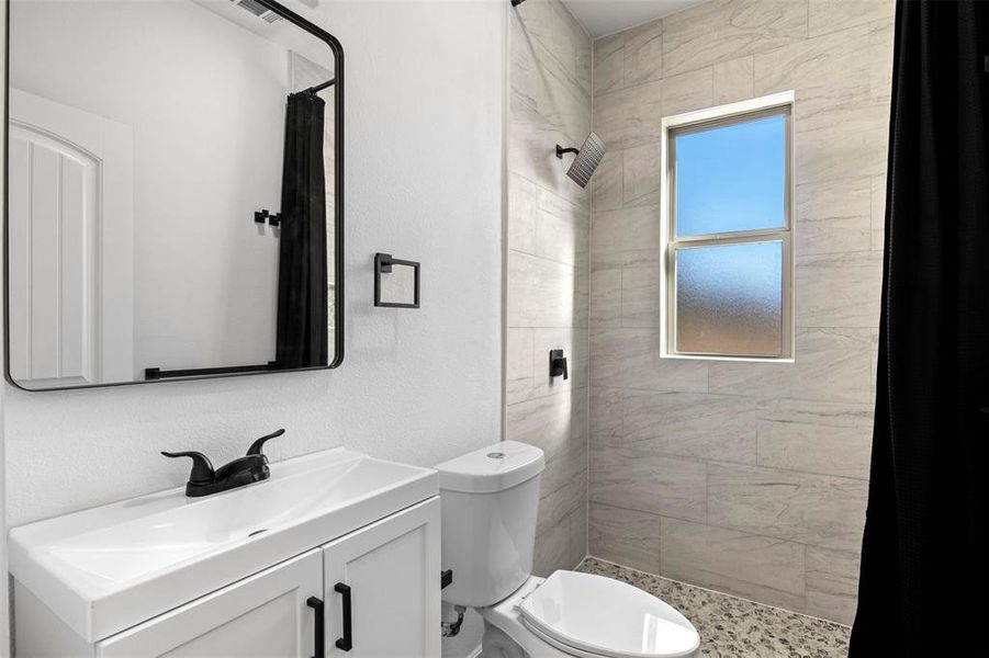 Bathroom with vanity, a shower stall, and a textured wall