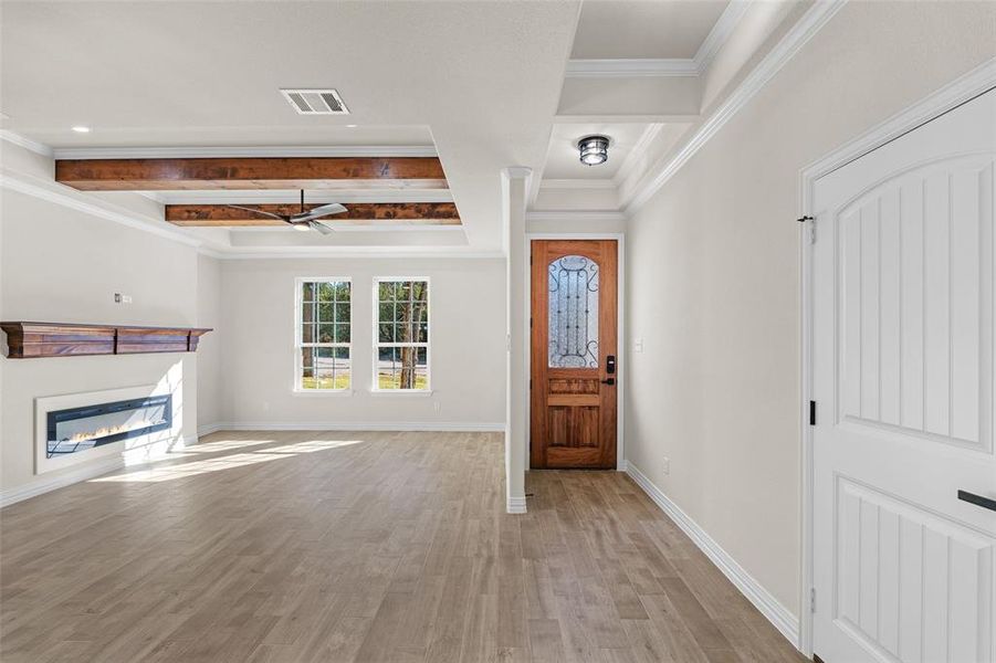 Entrance foyer featuring ceiling fan, beamed ceiling, ornamental molding, and light wood-type flooring