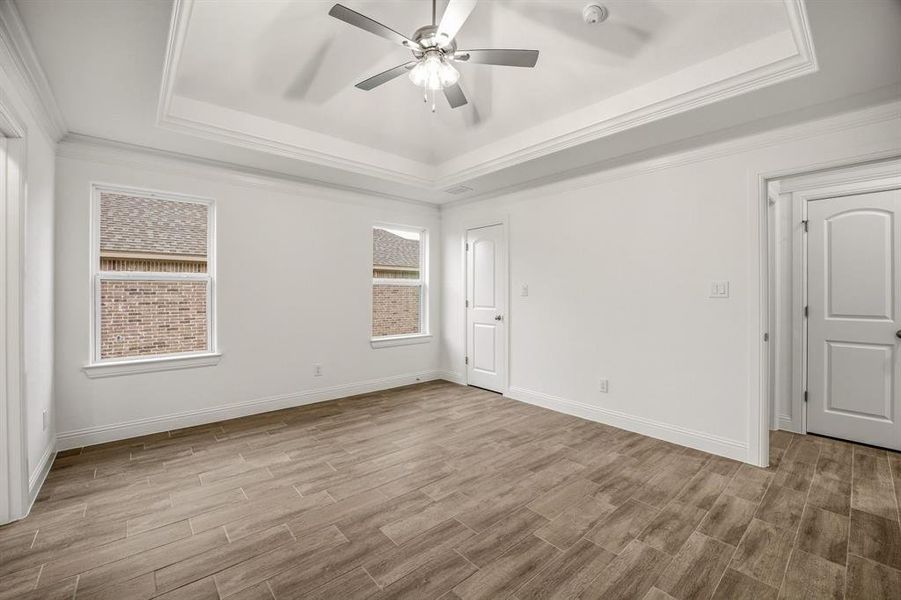 This room features wood-look tile flooring, white walls, and a tray ceiling with a ceiling fan