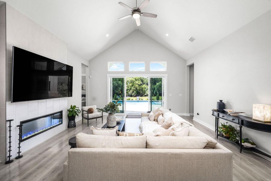 A grand vaulted ceiling elevates this living room with a linear fireplace and direct access to a private pool oasis.