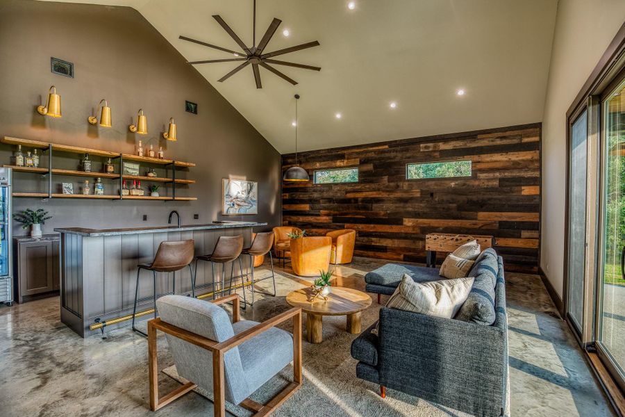 Living area featuring wood walls, high vaulted ceiling, wet bar, an accent wall, and recessed lighting Living area featuring wood walls, high vaulted ceiling, wet bar, an accent wall, and recessed lighting
