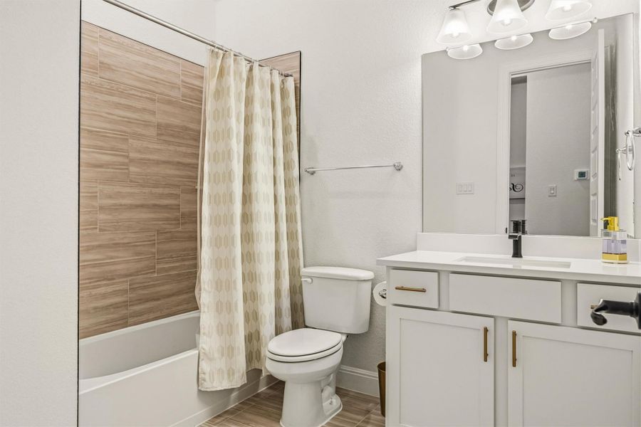Full bath featuring vanity, shower / bath combo with shower curtain, and wood tiled floors