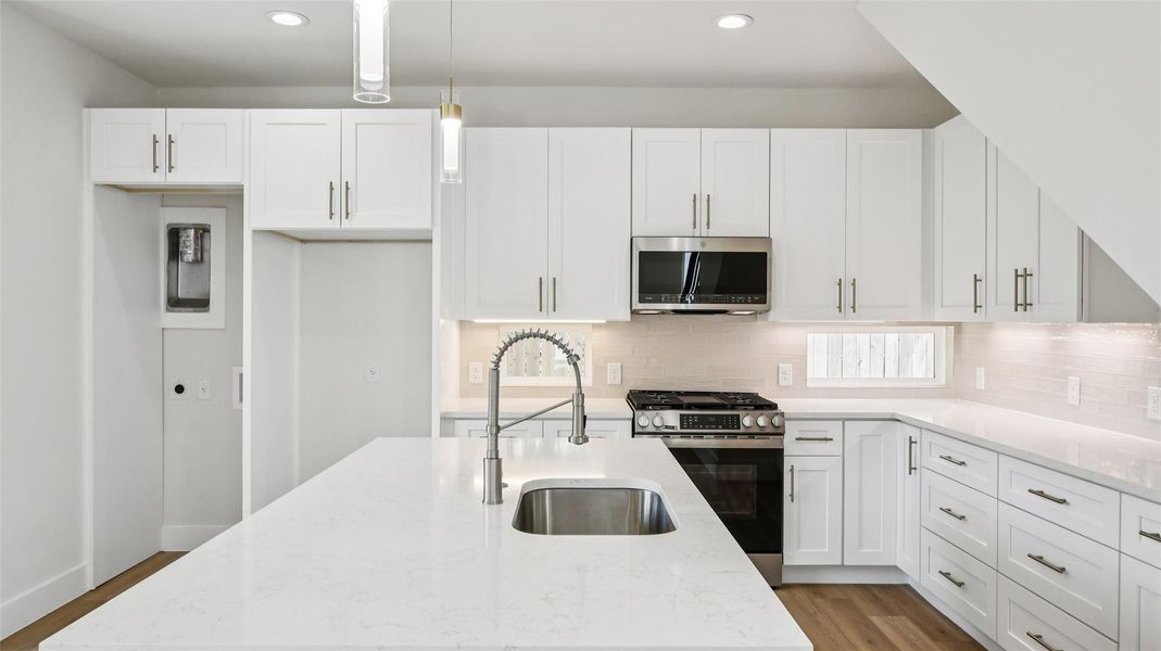 Kitchen with stainless steel appliances, white cabinets, light stone counters, light wood-style floors, and recessed lighting Kitchen with stainless steel appliances, white cabinets, light stone counters, light wood-style floors, and recessed lighting