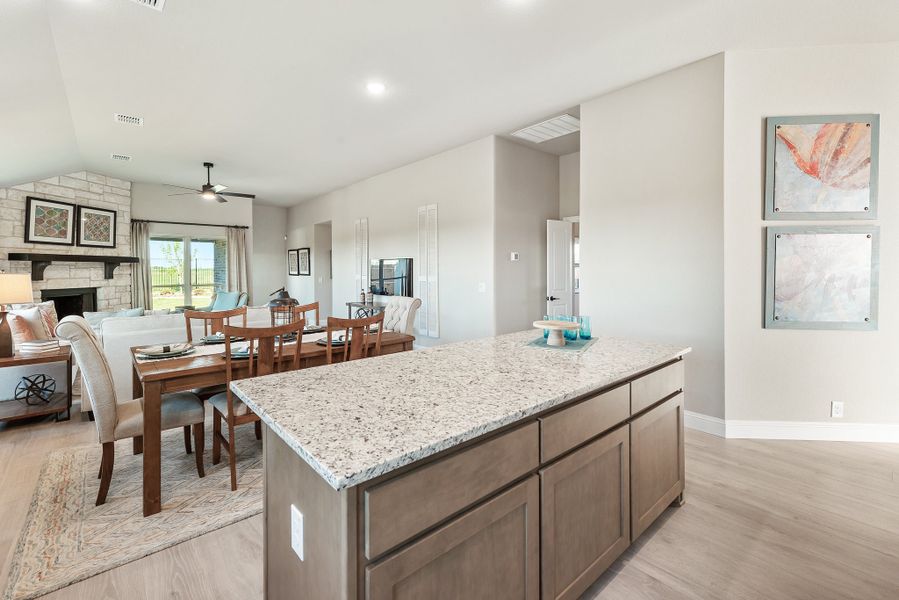 Kitchen island with granite countertop open to dining area and living room with stone fireplace Kitchen island with granite countertop open to dining area and living room with stone fireplace