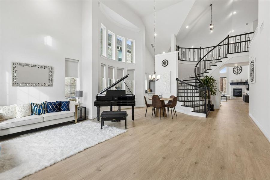 Two-story foyer featuring light wood-finish flooring, a grand spiral staircase with black iron balusters, and a curved wall of windows