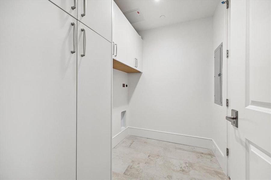 Laundry room in unit with built-in floor-to-ceiling cabinets.