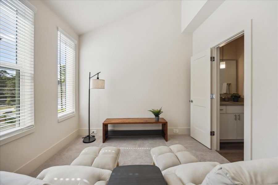 High ceilings and oversized windows fill the room with natural light, while plush carpeting adds comfort underfoot. With direct access to a full bathroom, it’s as functional as it is inviting.