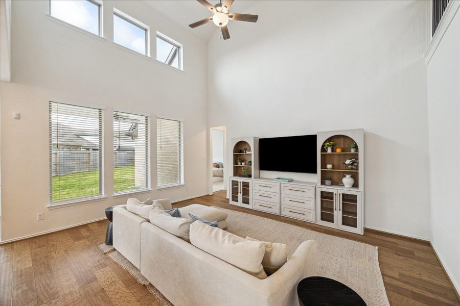 The open family room features soaring ceilings and expansive windows that fill the space with natural light, creating a bright and welcoming atmosphere.