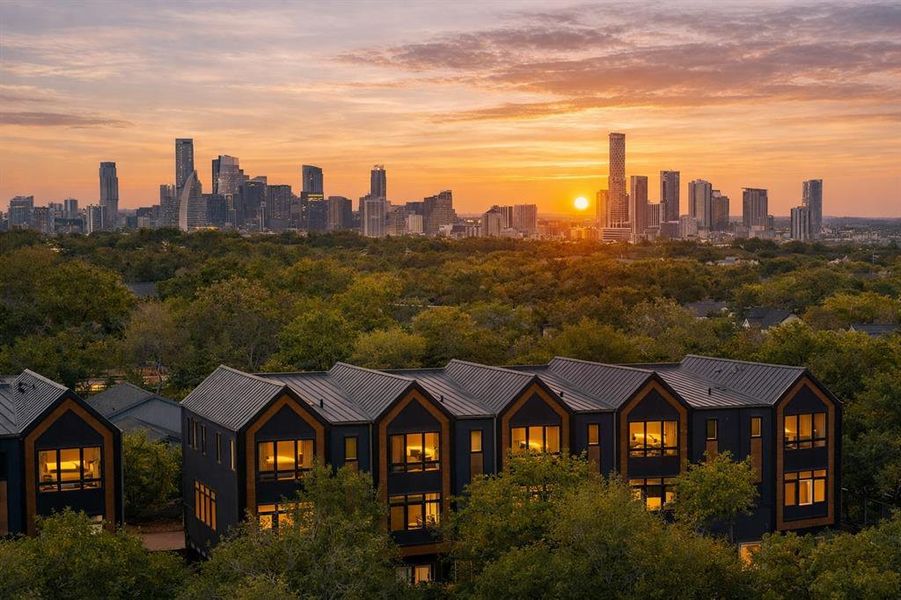 An aerial panorama capturing the metropolitan skyline at sunset with homes nestled among mature trees.