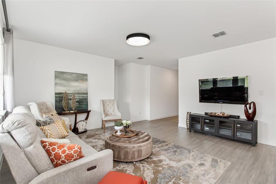 Spacious living area featuring light-colored flooring, white walls, and a contemporary ceiling light fixture