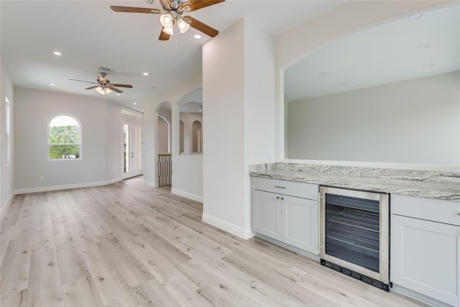 Interior space with wine cooler, ceiling fan, and light hardwood / wood-style flooring