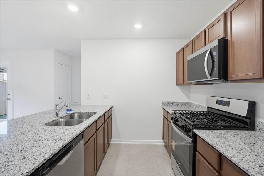 The kitchen features high ceilings, recessed lighting, Woodmont Cody cabinets in Ginger stain, granite countertops in Luna Pearl, SS appliances including microwave, and a pantry all overlooking your huge Great Room.