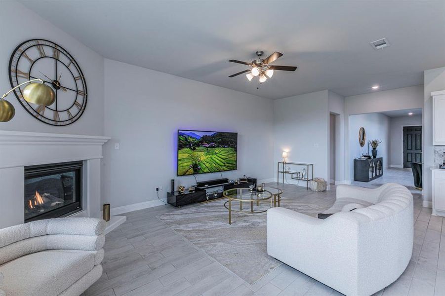 Living room with a ceiling fan, a glass covered fireplace, recessed lighting, and light wood finished floors Living room with a ceiling fan, a glass covered fireplace, recessed lighting, and light wood finished floors