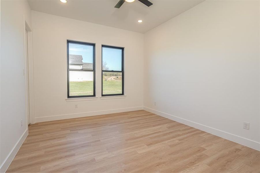 Empty room with ceiling fan and light hardwood / wood-style floors