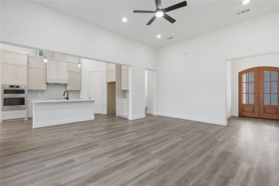 Open-concept living space with wood-finish flooring, vaulted ceilings, and recessed lighting