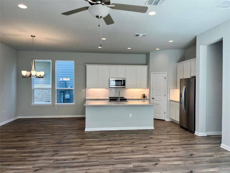 Kitchen featuring white cabinetry, stainless steel appliances, recessed lighting, an island with sink, and a chandelier