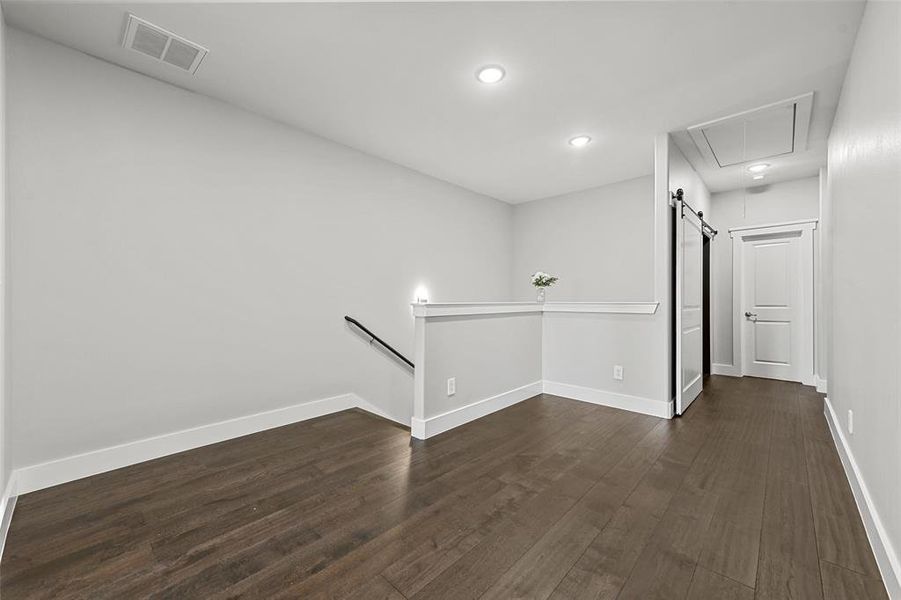 Empty room with dark wood-type flooring and a barn door