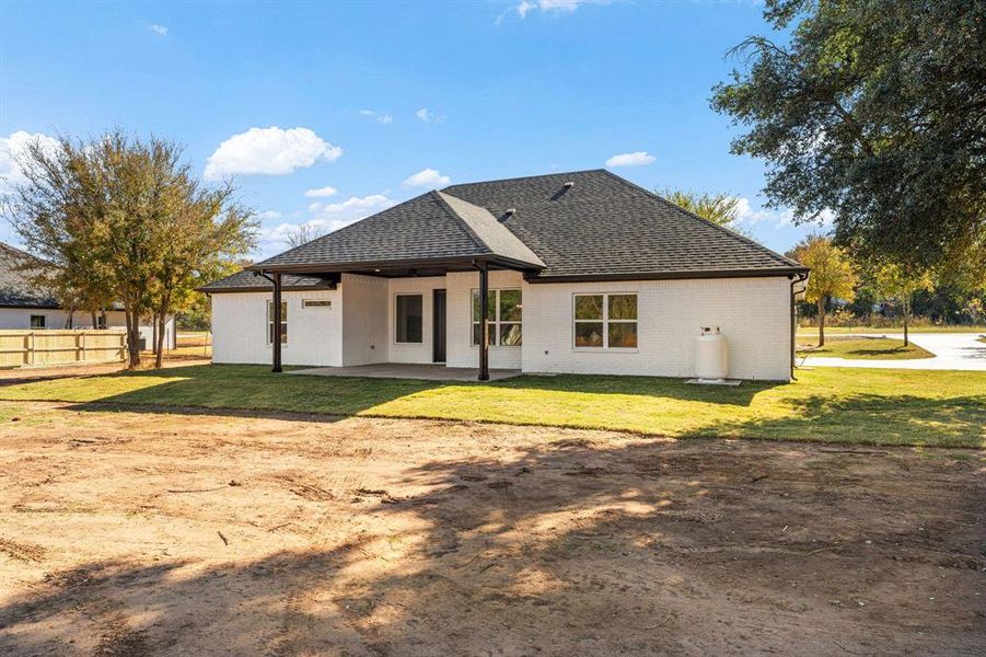 Rear view of house featuring brick siding, a patio area, and a shingled roof