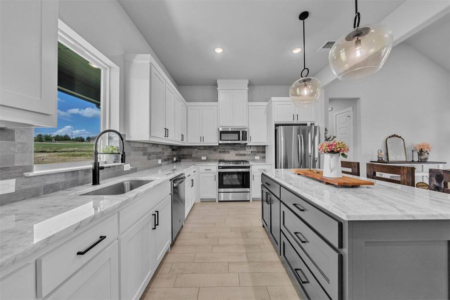 Modern kitchen featuring white shaker cabinetry, stainless steel appliances, a large center island with a stone countertop, a tile backsplash, and wood-finish flooring