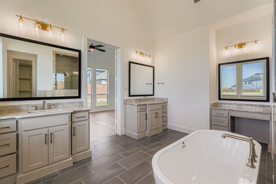 Full bathroom featuring two vanities, a freestanding bath, wood finish floors, a ceiling fan, and a stall shower